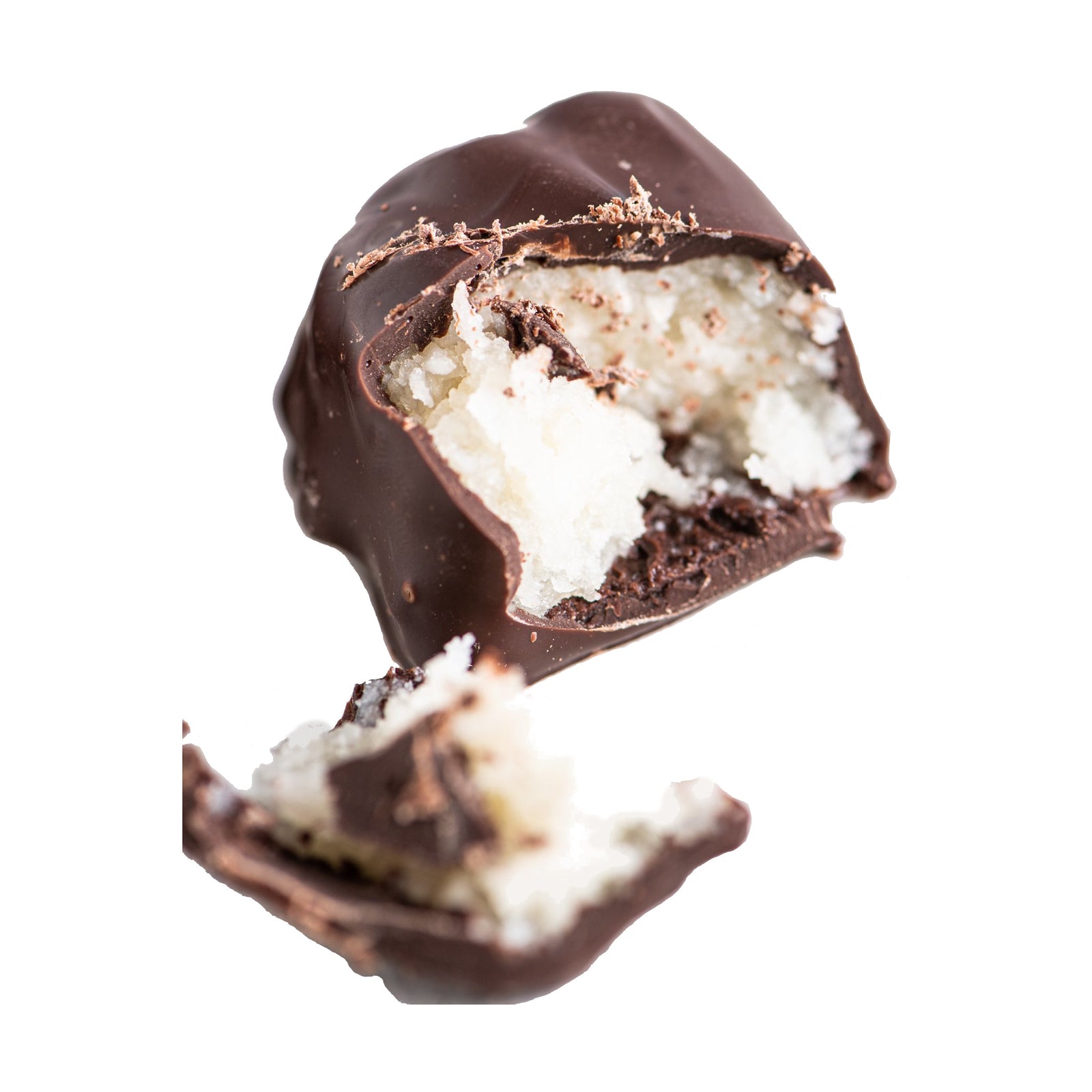 A close-up of a broken chocolate truffle reveals a creamy, white coconut filling inside. The chocolate shell is cracked, showing the textured, moist coconut center against a white background.