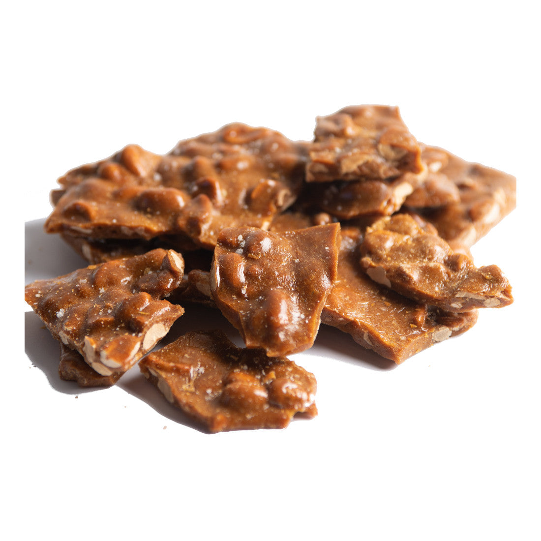 Pieces of crunchy peanut brittle with a shiny, caramelized surface and visible peanuts, arranged in a small pile on a white background.