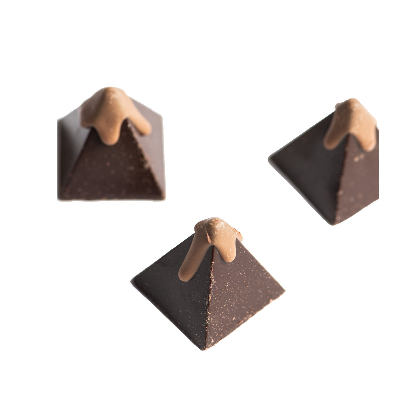 Three pyramid-shaped dark chocolates with light brown chocolate drizzled on top, displayed against a white background.