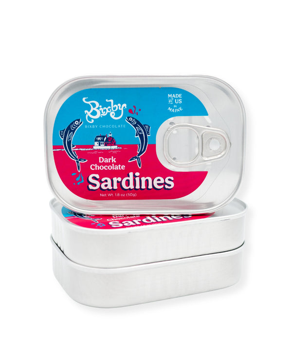 Two stacked tins from Bixby Chocolates, labeled "Chocolate Sardines, Tinned," feature blue and pink fish graphics and a pull-tab. These sardine-shaped artisanal chocolates make a quirky Maine souvenir or unique gift.