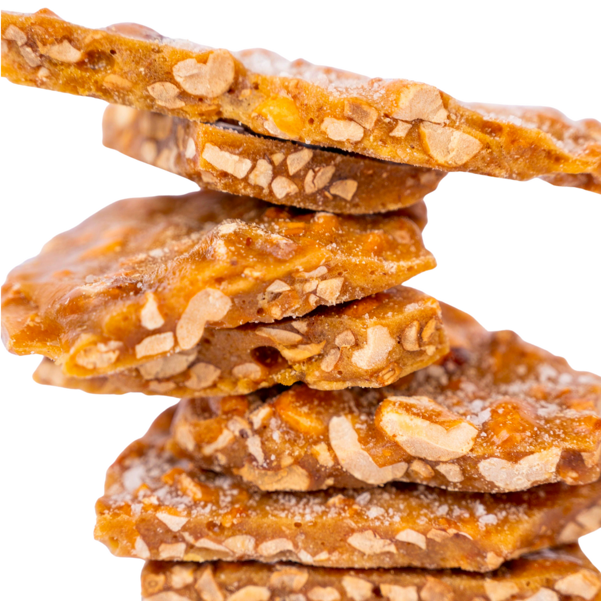 A close-up of several pieces of Bixby Chocolates’ Beer Brittle Gift Box stacked together, highlighting the crunchy golden caramel and embedded almond slices against a white background.