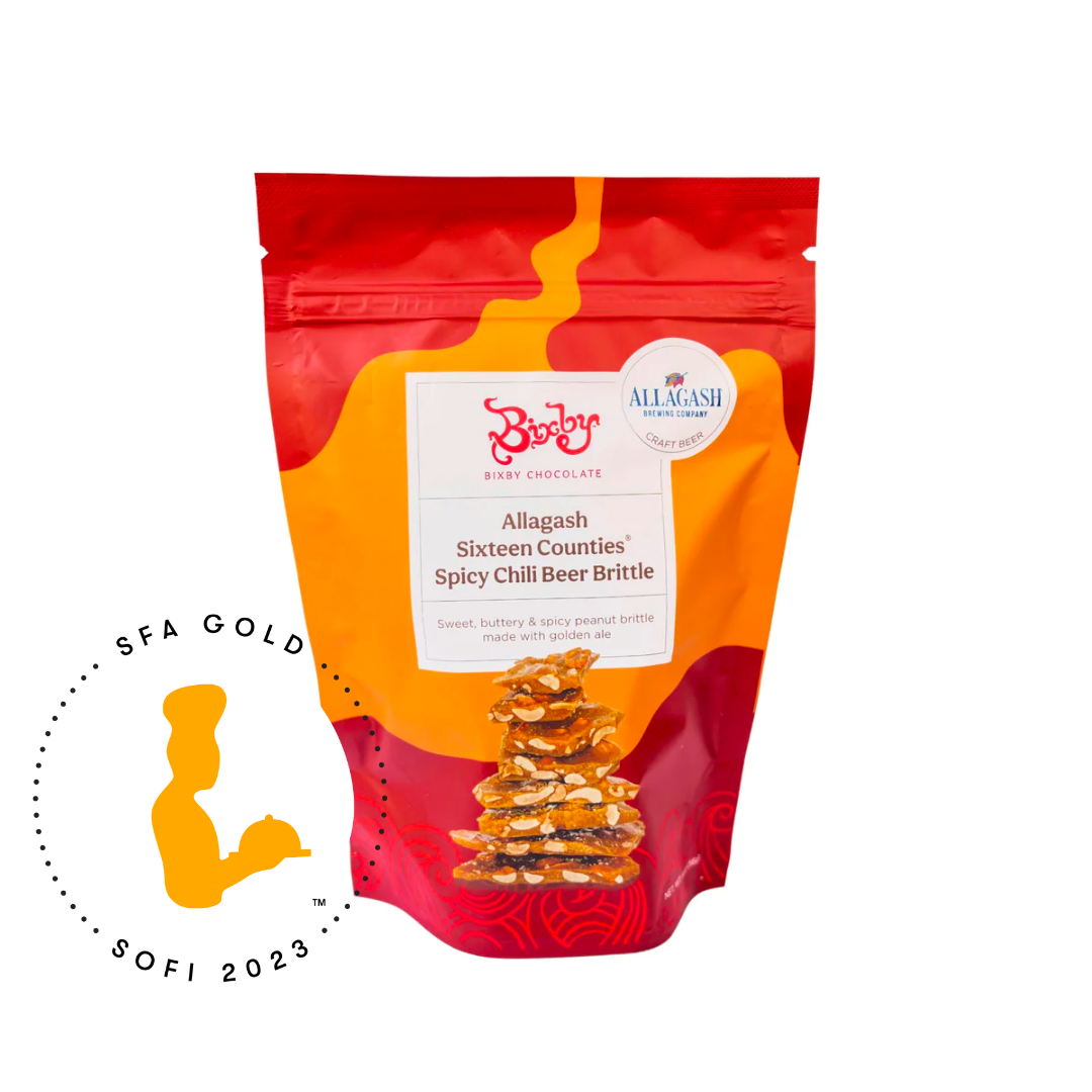 A Beer Brittle Gift Box from Bixby Chocolates stands upright beside a gold SFA Gold SOFI 2023 award logo featuring a stylized silhouette.