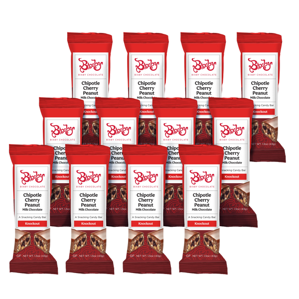 Twelve Knockout bars from Bixby Chocolates are arranged in three rows, each red and white wrapper highlighting milk chocolate with chipotle, peanuts, and Bing cherries on the front.