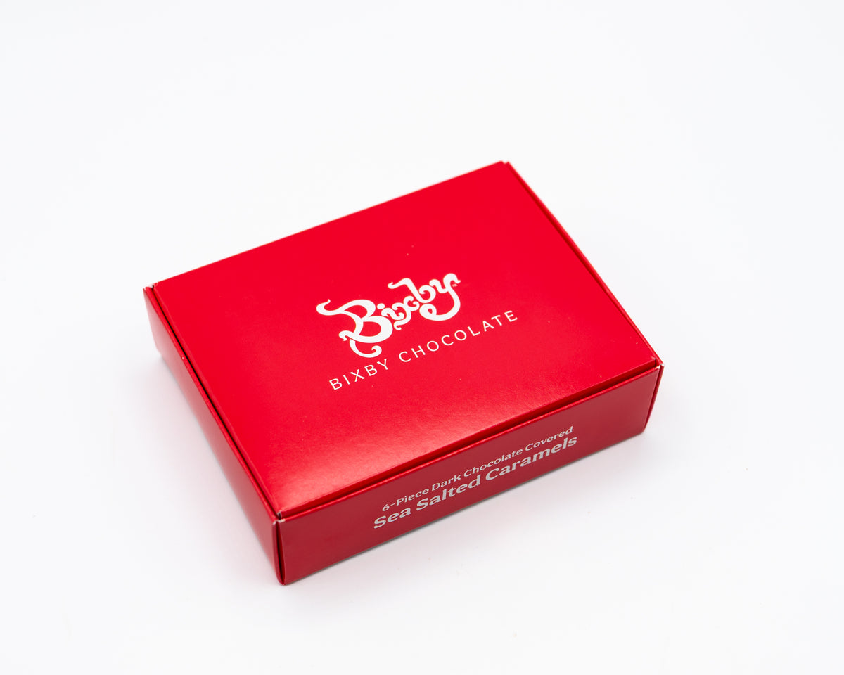 The Bixby Chocolates Chocolate Sea Salted Caramels Gift Box features 4 artisanal dark chocolate sea salted caramels in a red rectangular box, beautifully displayed on a white background—an ideal chocolate caramel gift.