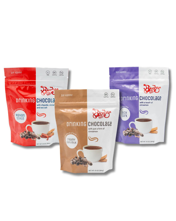 Three packages of drinking chocolate with different colored packaging on a white background