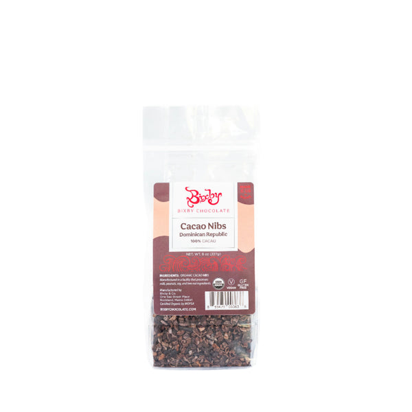 A clear, resealable bag of Bixby Chocolates Organic Dominican Republic Cacao Nibs features a brown label with product details and displays the crunchy superfood cacao nibs inside.
