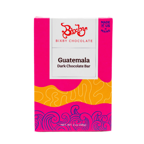 A vibrant pink and orange Bixby Chocolates package labeled Organic Guatemalan 70% Dark Chocolate Bar, with abstract wave patterns, made in Maine, and a net weight of 2 oz (56 g).