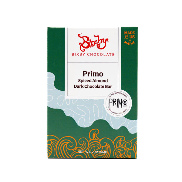 A 2oz (56g) box of Bixby Chocolates Primo Dark Chocolate Spiced Olive Oil Roasted Almond Bar, featuring a green and gold wave design, made in Maine, USA with organic cocoa beans from the Dominican Republic.