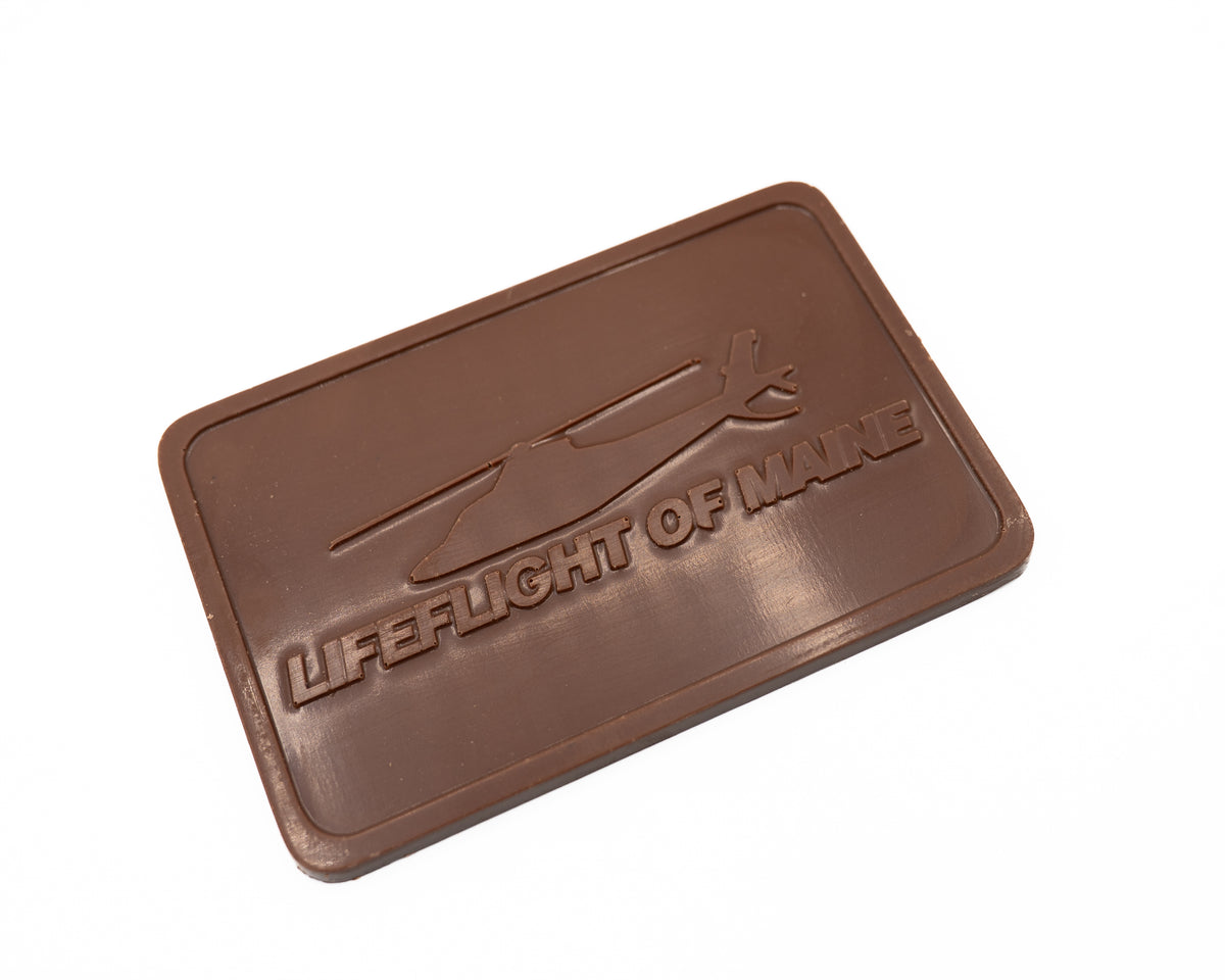 The LifeFlight Maine Sea Salt Milk Chocolate Bar by Bixby Chocolates features a rectangular shape with an embossed helicopter and "LIFEFLIGHT OF MAINE," honoring Maine's vital emergency air transport service.
