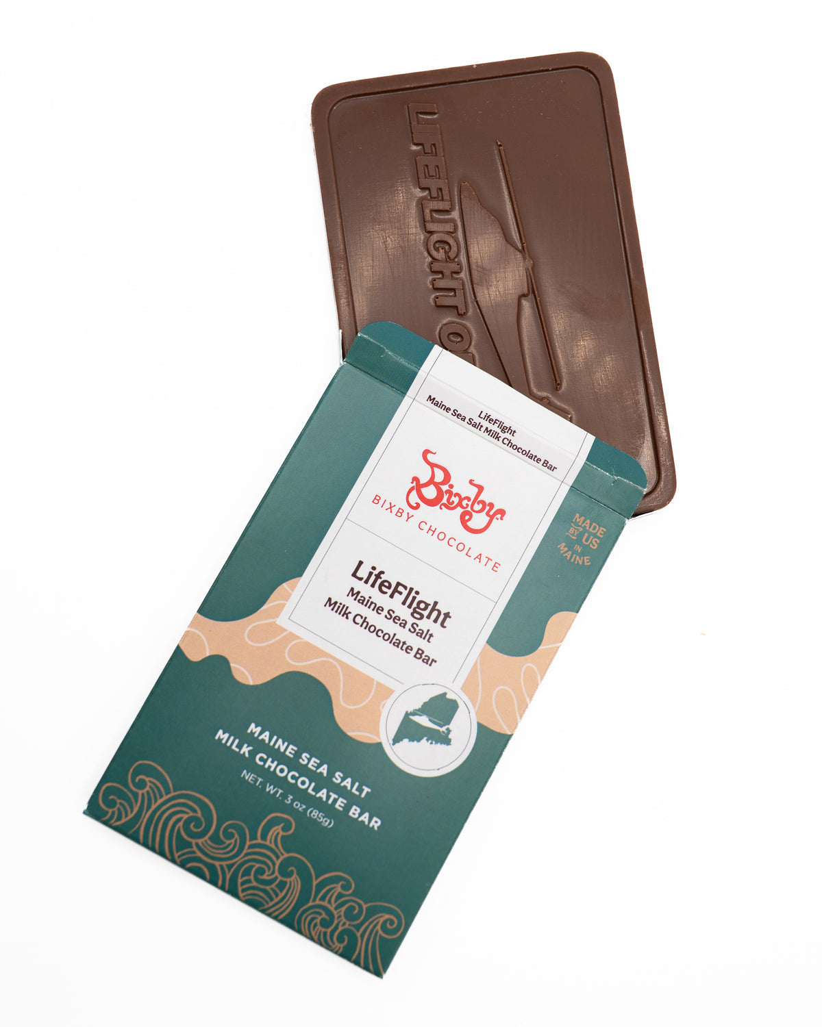 A Bixby Chocolates LifeFlight Maine Sea Salt Milk Chocolate Bar peeks out from its teal and beige wrapper, displaying sea salt chocolate with a helicopter image and "LIFEFLIGHT," honoring emergency air transport.