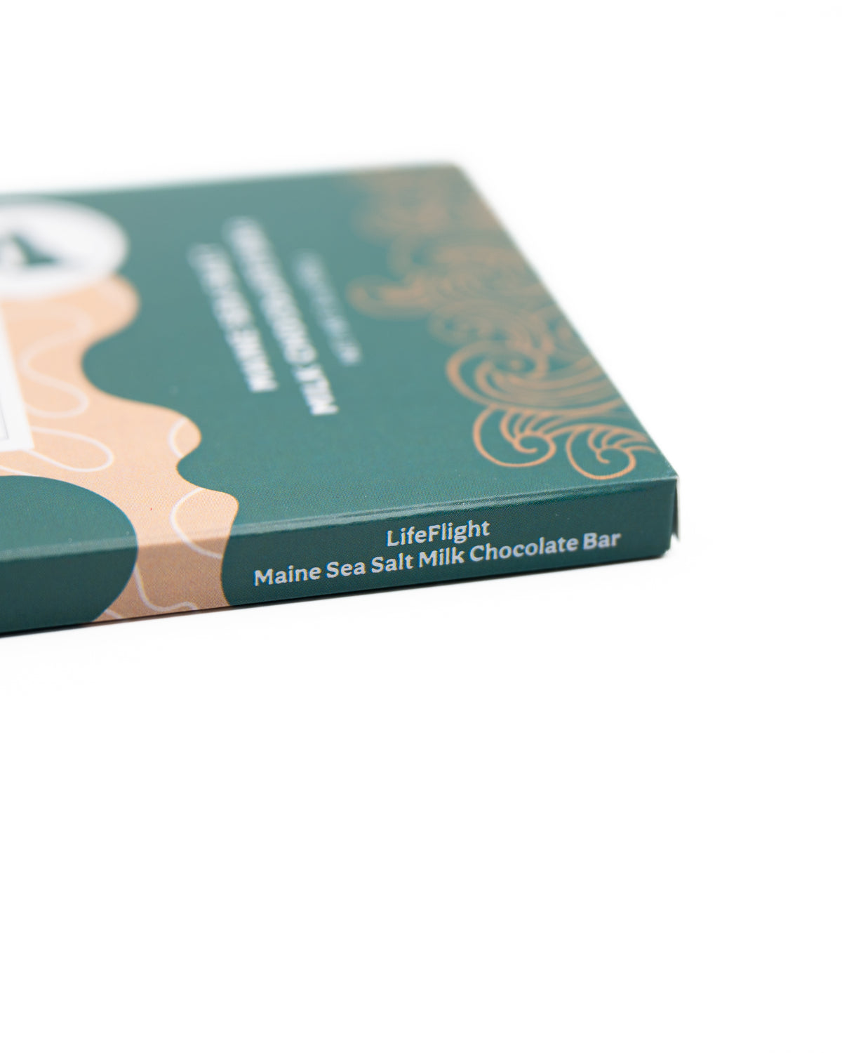 A close-up of the LifeFlight Maine Sea Salt Milk Chocolate Bar wrapper by Bixby Chocolates, featuring green and peach colors—celebrating emergency air transport with delicious Maine sea salt milk chocolate.
