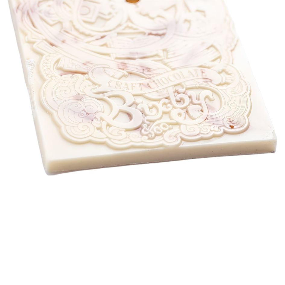 A close-up of Bixby Chocolates' Organic Crème Brûlée White Chocolate Bar, decorated with embossed patterns and the words CRAFT CHOCOLATE among its ornate, organic design.