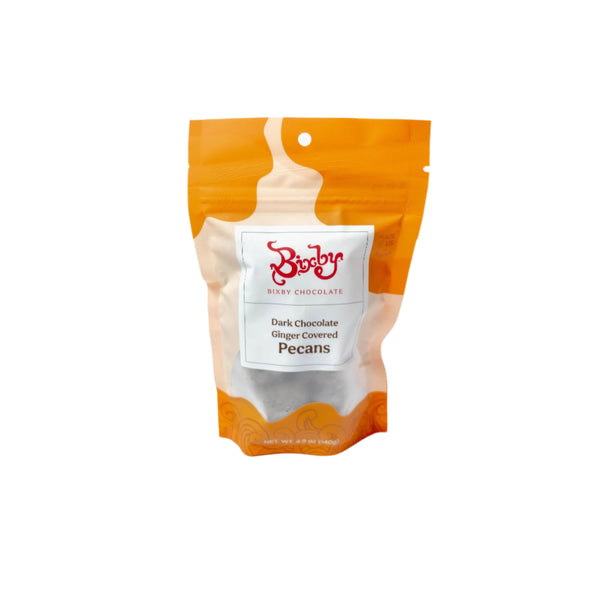 A resealable orange and clear bag of Bixby Chocolates Dark Chocolate Ginger Covered Pecans stands upright on a white background, featuring pecans and crystallized ginger coated in rich dark chocolate.