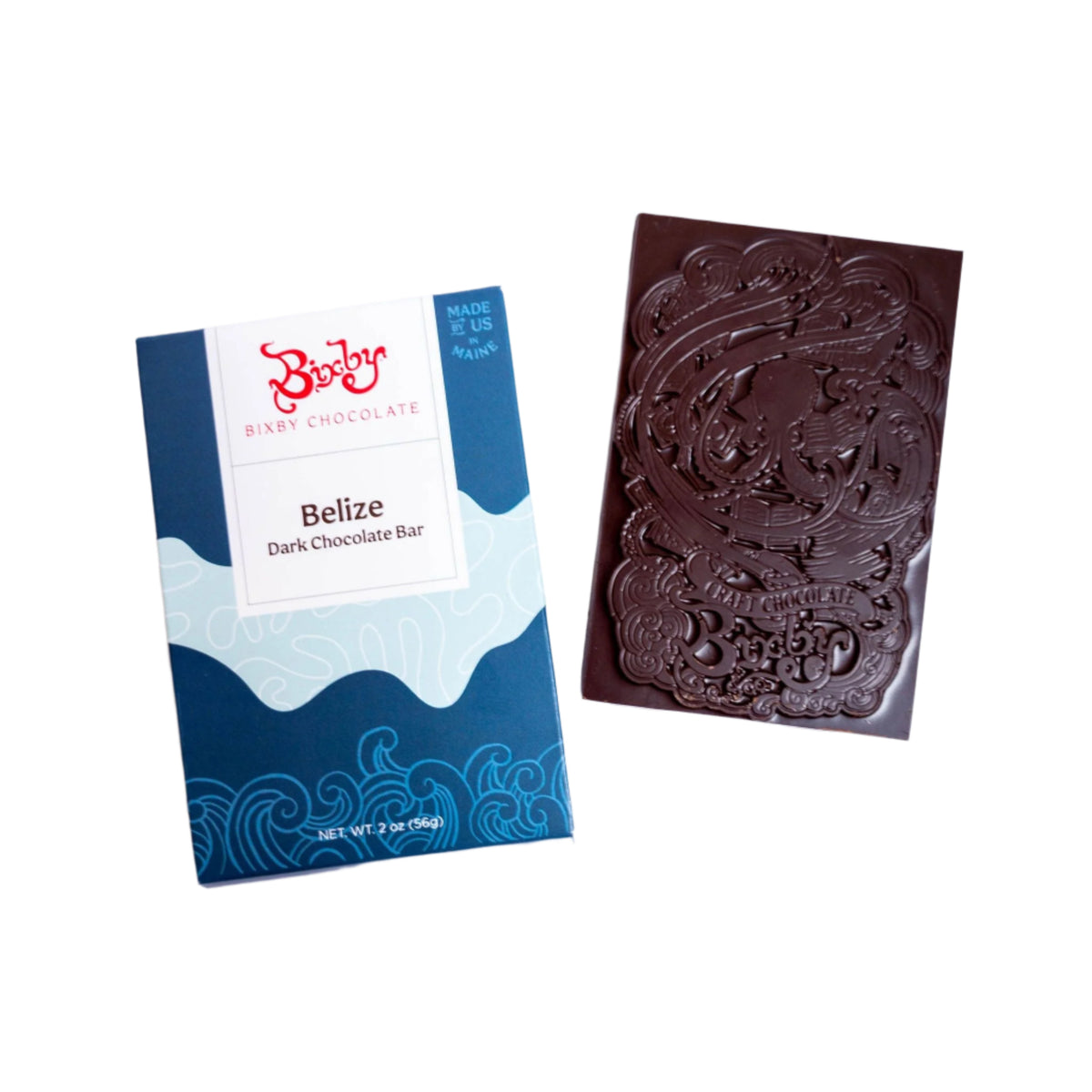 An unwrapped Bixby Chocolates Organic Belize 70% Dark Chocolate Bar lies beside its blue and white packaging, displaying the intricate design on the chocolate, which is crafted from ethically sourced Belizean cacao.