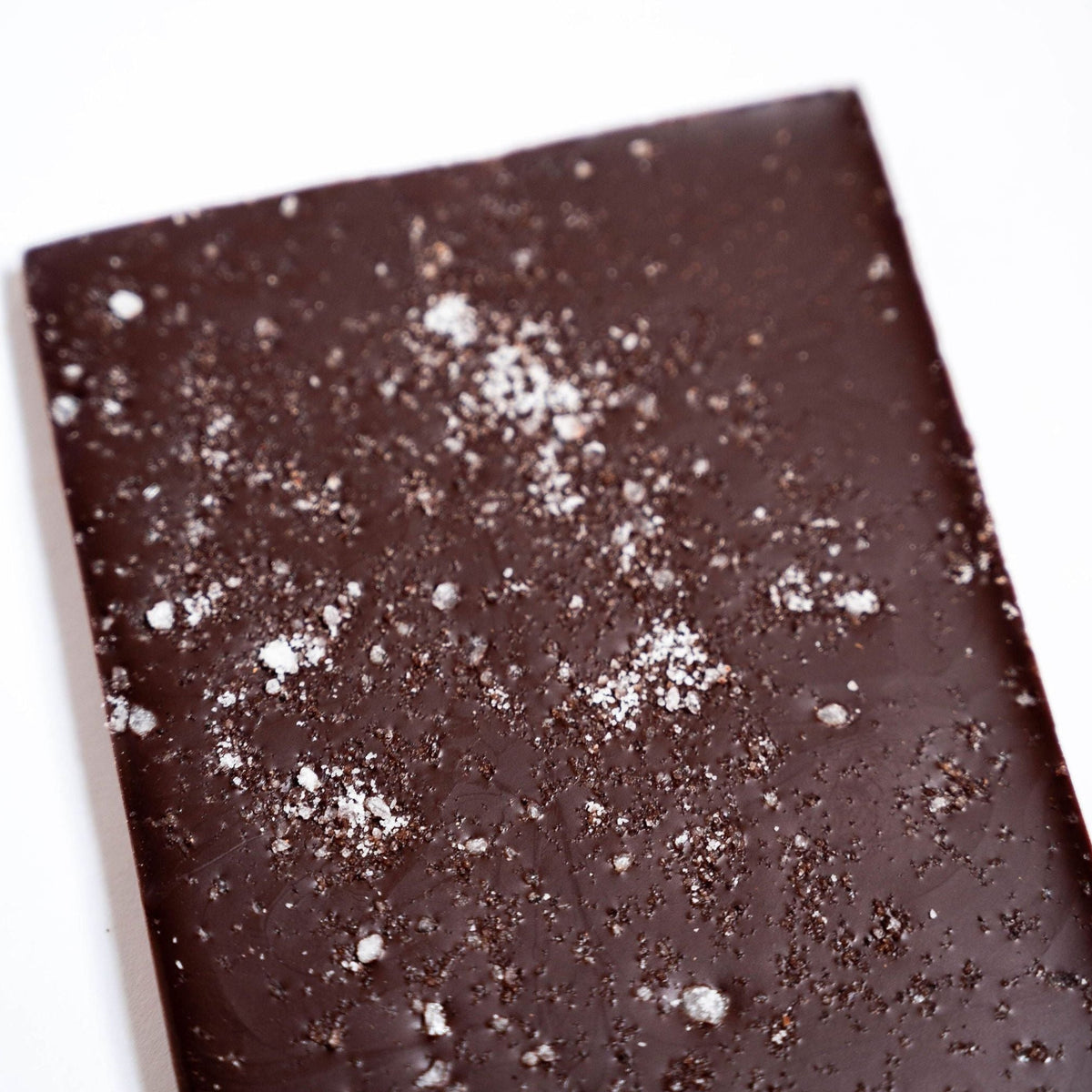 A close-up of the Bixby Chocolates Organic Dark Chocolate Maine Sea Salt Bar, a rectangular bar sprinkled with coarse sea salt, set against a white background.