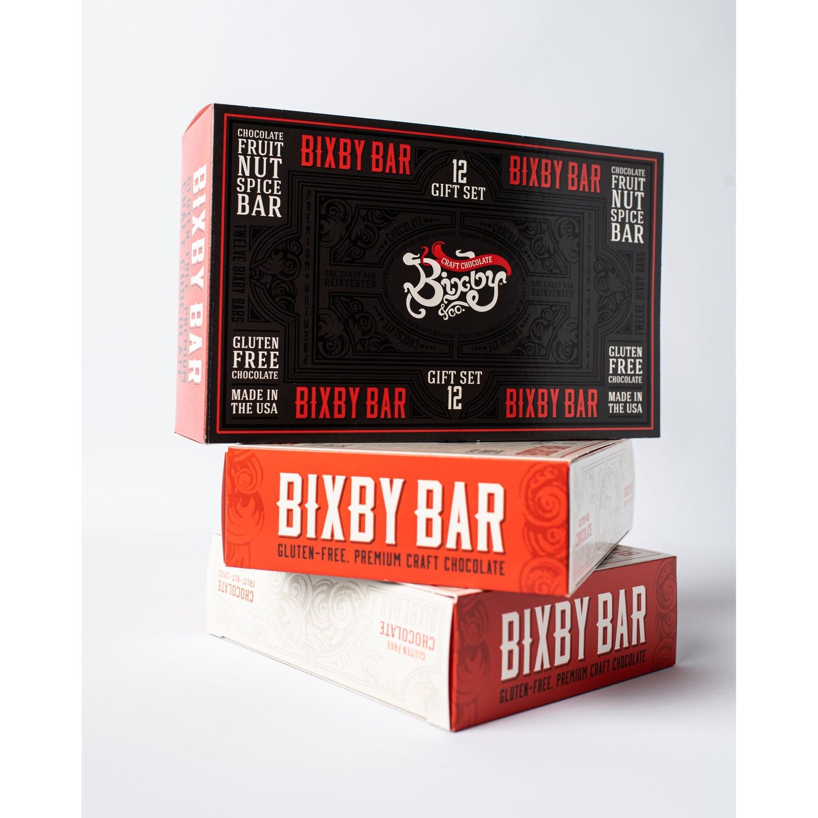 Three Bixby Chocolates Assorted Gift Boxes (6 or 12 bars) are stacked in black, red, and white. Labeled Gluten-Free and Made in the USA, these chocolate bars make a perfect gift.