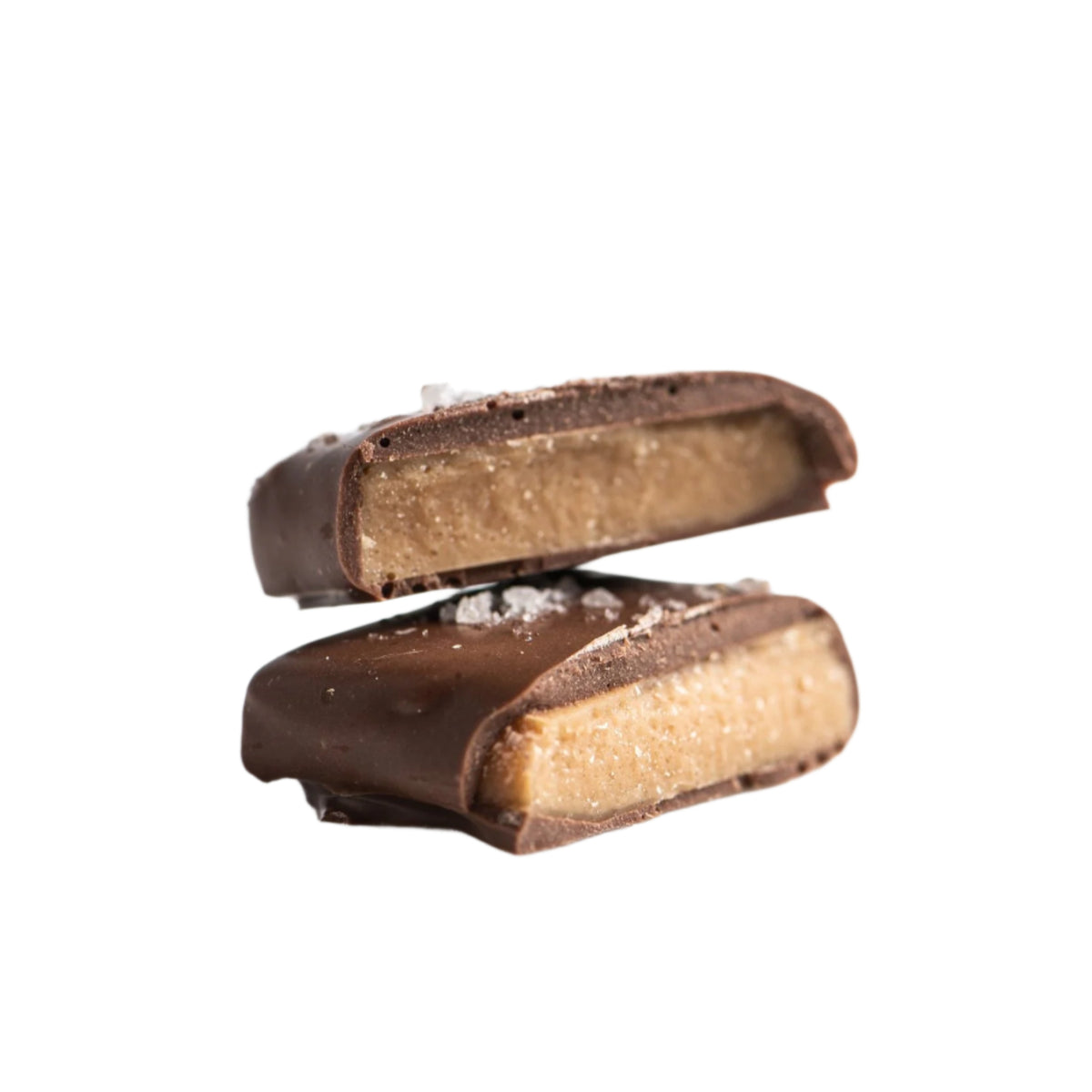 Two pieces of Bixby Chocolates Milk Chocolate Toffee are stacked on a white background, revealing the smooth caramel filling inside and a sprinkle of coarse salt on top.