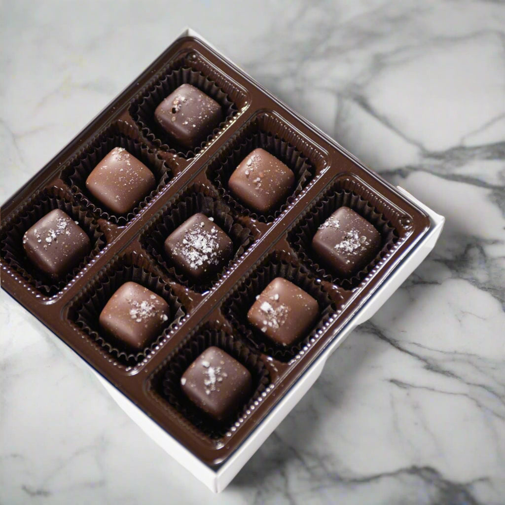 The Bixby Chocolates 32 piece Milk & Dark Chocolate Sea Salted Caramel Gift Box features assorted truffles filled with sea salted caramel, each topped with sea salt and elegantly arranged in a brown tray.