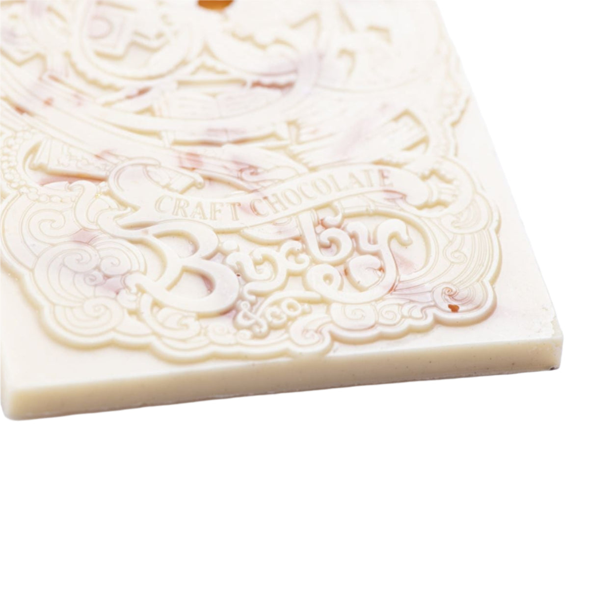 The Bixby Chocolates Organic Crème Brûlée White Chocolate Bar, crafted with organic ingredients, features intricate swirling designs and "CRAFT CHOCOLATE" embossed on a white background.